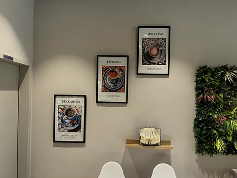 Drei gerahmte Kaffee-Poster neben der Pflanzenwand